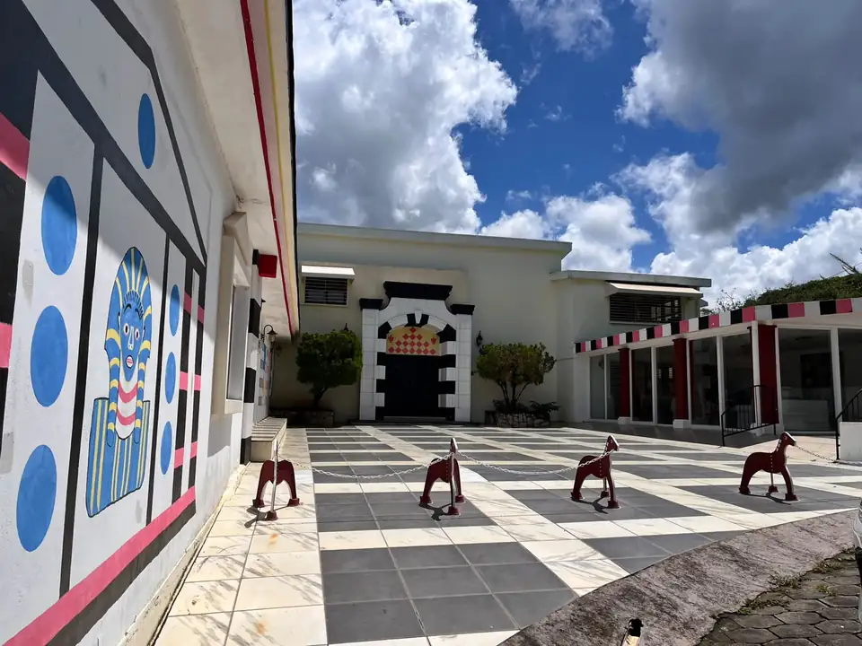 La Cour de la Fresque — Façade peinte et dallage en damier menant au portail principal.