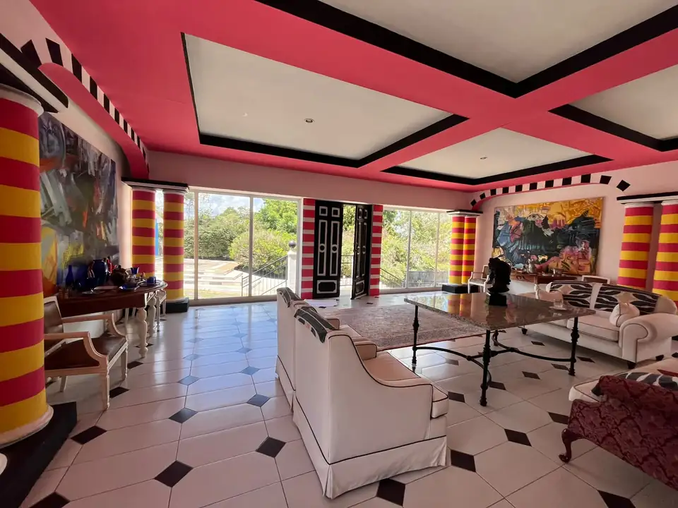 Salon du Jardin — Baies vitrées sur le jardin, encadrées de rouge et d'or.